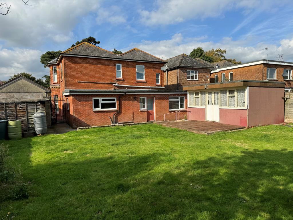 Lot: 154 - THREE-BEDROOM GROUND FLOOR APARTMENT FOR IMPROVEMENT WITH GARDENS AND GARAGE - Garden showing rear of building and grass lawn